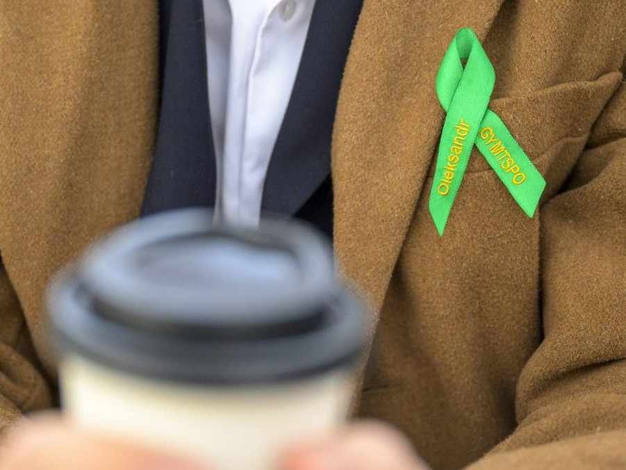 Študent s kávou a maturitnou stužkou.