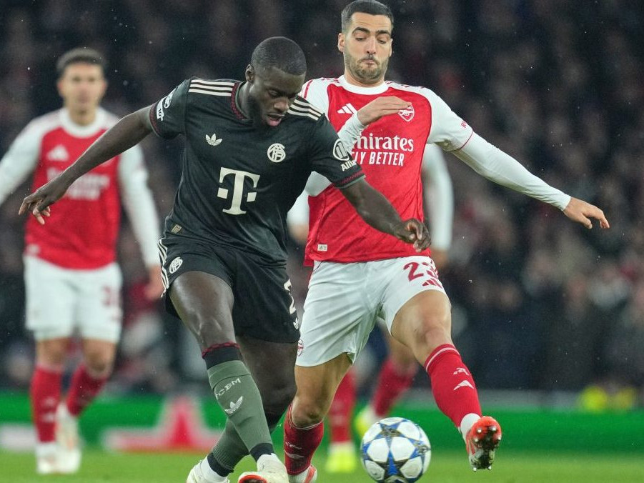 Hráč Bayernu Dayot Upamecano (vpredu) uniká s loptou pred Mikelom Merinom z Arsenalu.