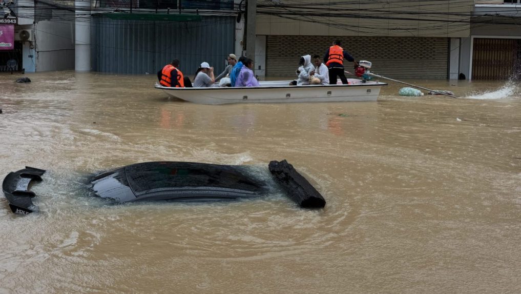 Thajská záchranná posádka na člne prechádza okolo ponoreného auta.