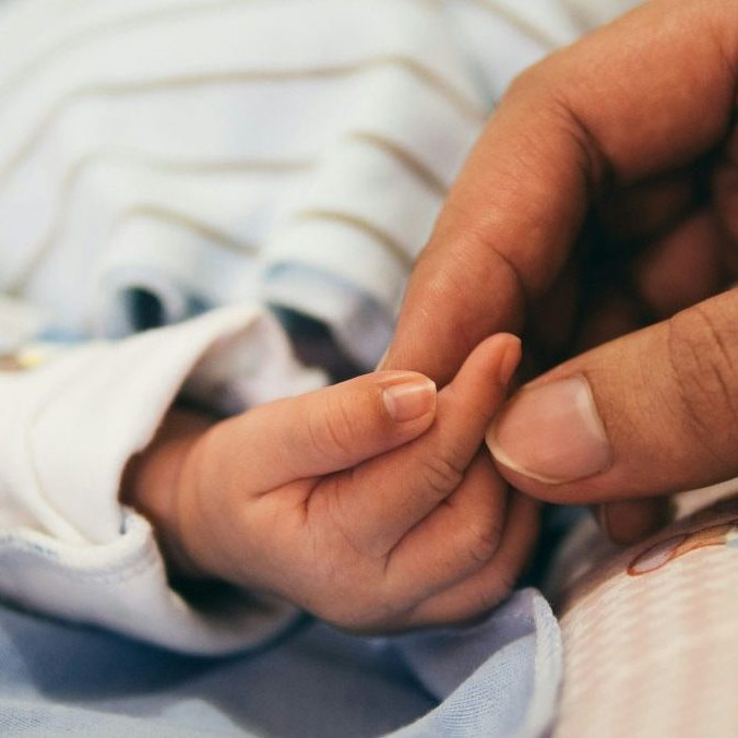 Na snímke ruka dieťaťa, ktorú drží ruka dospelej osoby.