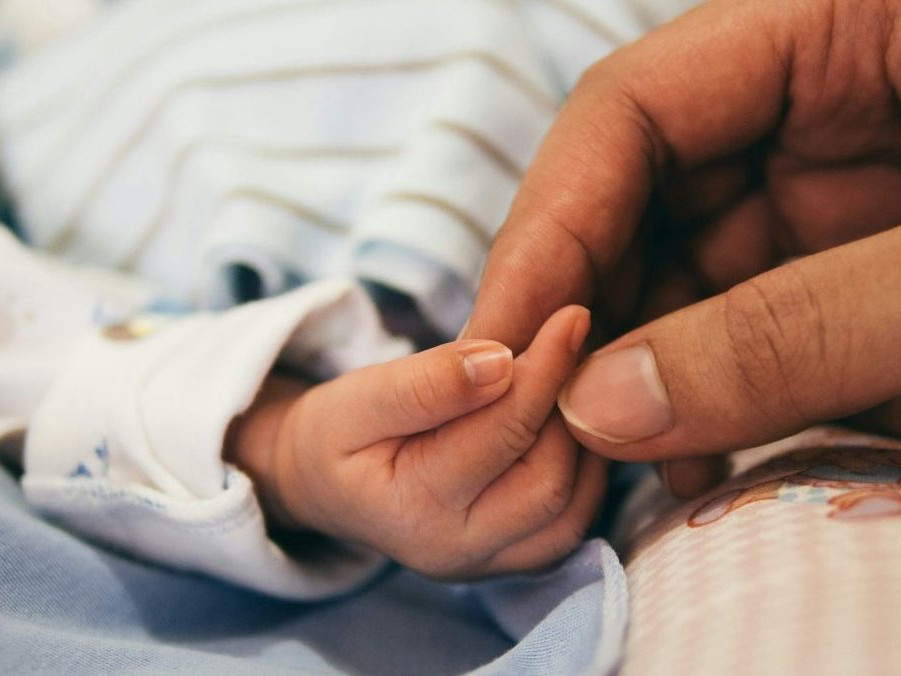 Na snímke ruka dieťaťa, ktorú drží ruka dospelej osoby.