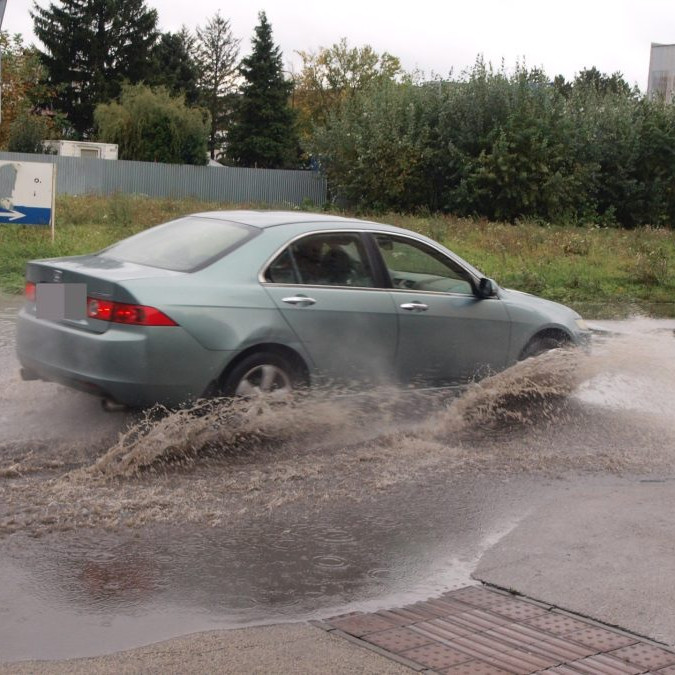 Na snímke osobné auto jazdí po zaplavenej ceste v dôsledku intenzívneho dažďa.