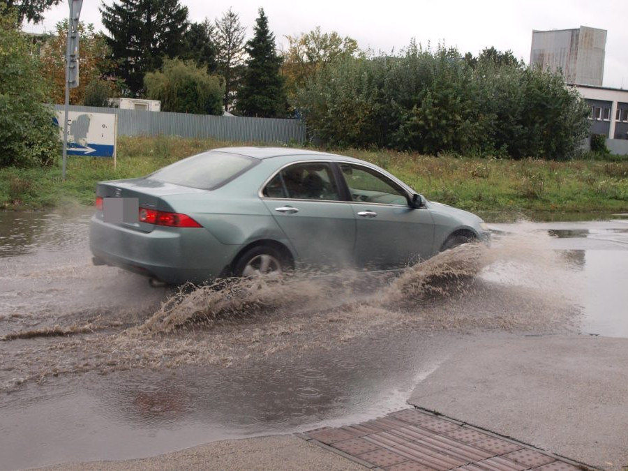Na snímke osobné auto jazdí po zaplavenej ceste v dôsledku intenzívneho dažďa.