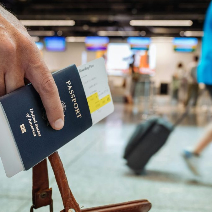 Osoba na fotografii drží v ruke medzi prstami pas občana Spojených štátov amerických.