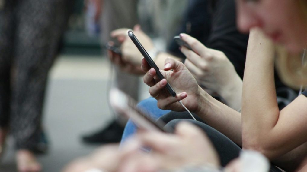 Na snímke ľudia, ktorí držia v ruke telefóny.