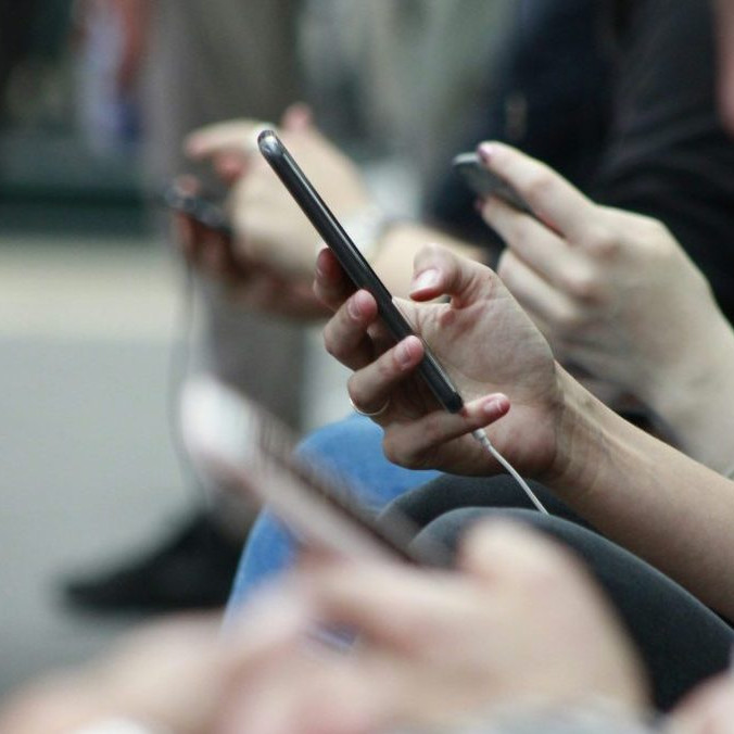 Na snímke ľudia, ktorí držia v ruke telefóny.