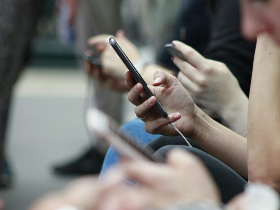 Na snímke ľudia, ktorí držia v ruke telefóny.