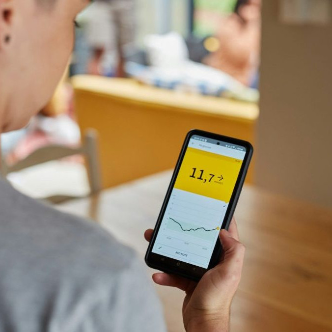 Žena s cukrovkou sleduje výsledky merania hladiny cukru v krvi v mobilnej aplikácii.