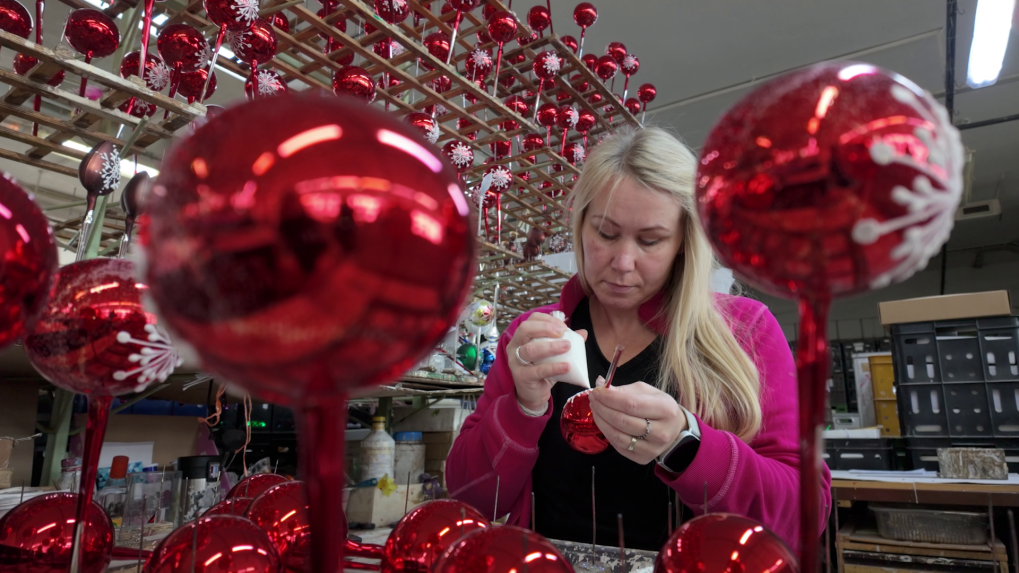 Na snímke žena zdobí vianočnú guľu v popredí sú vianočné gule.