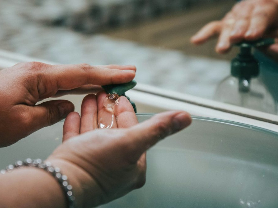 Na snímke si osoba umýva ruky v umývadle tekutým mydlom.