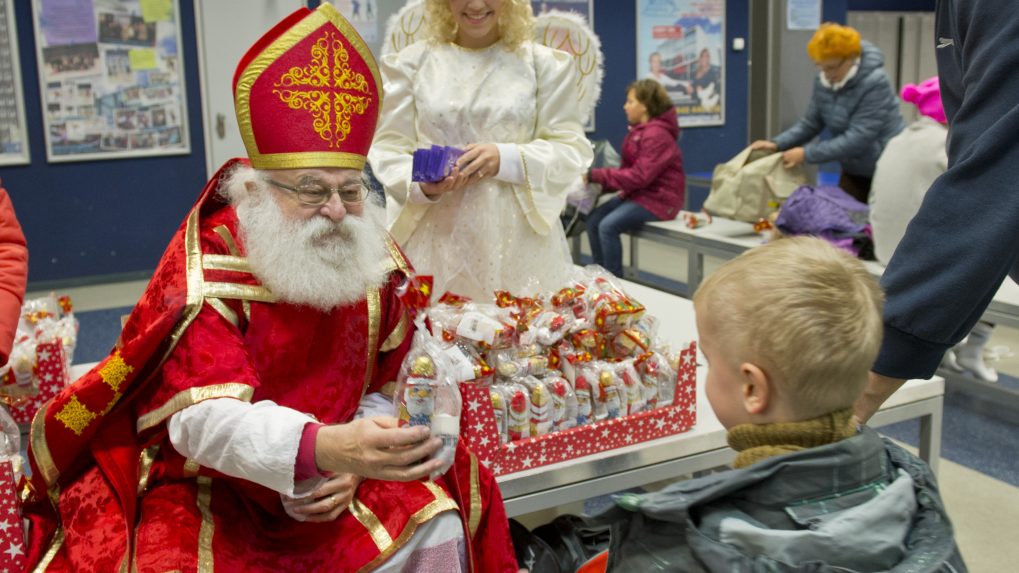 Na snímke Mikuláš rozdáva deťom darčeky. V pozadí čert a anjel.