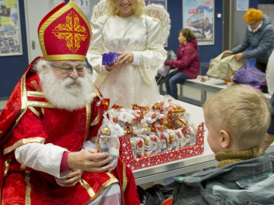 Na snímke Mikuláš rozdáva deťom darčeky. V pozadí čert a anjel.