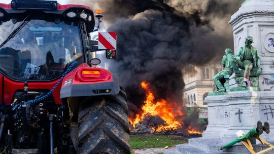 Na snímke je traktor a v pozadí horí odpad v blízkosti europarlamentu.