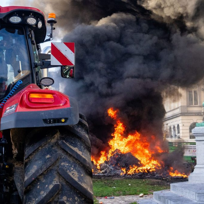 Na snímke je traktor a v pozadí horí odpad v blízkosti europarlamentu.