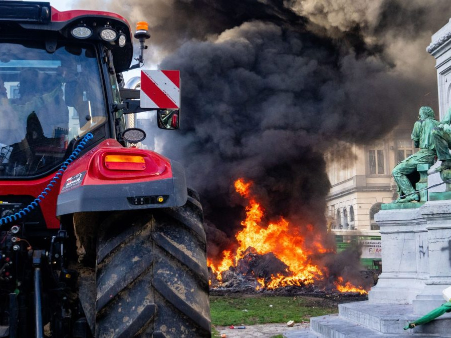 Na snímke je traktor a v pozadí horí odpad v blízkosti europarlamentu.