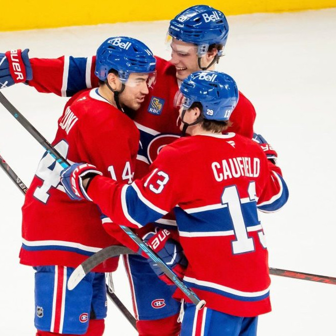 Hráč Montrealu Canadiens Nick Suzuki oslavuje so spoluhráčmi Jurajom Slafkovským a Coleom Caufieldom.
