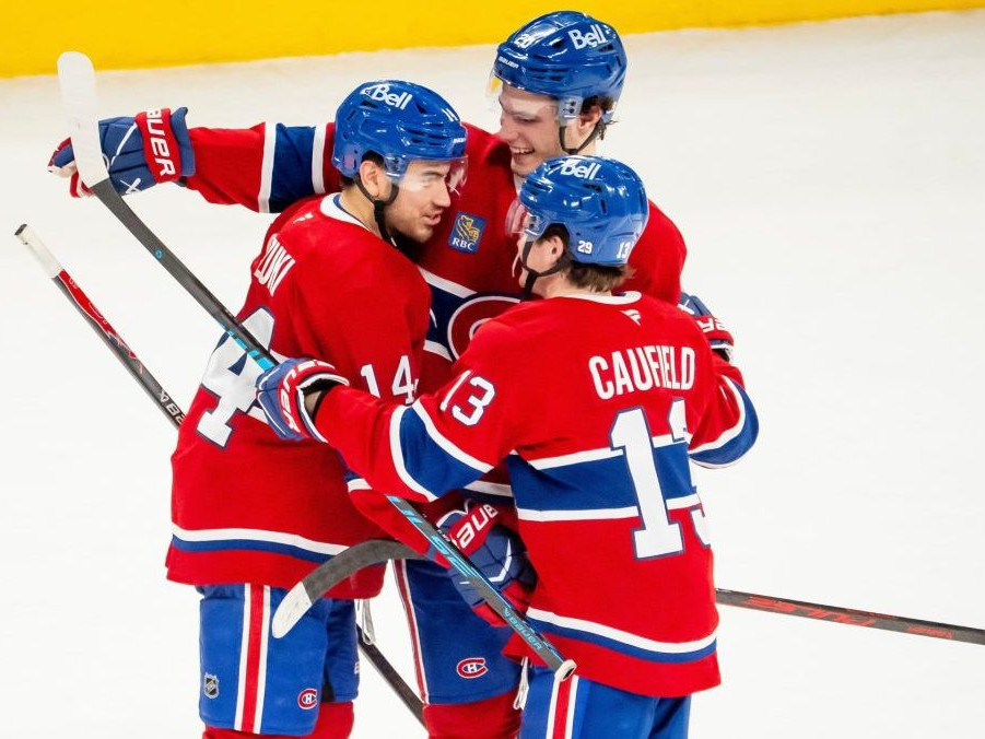 Hráč Montrealu Canadiens Nick Suzuki oslavuje so spoluhráčmi Jurajom Slafkovským a Coleom Caufieldom.