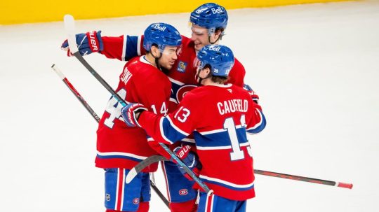 Hráč Montrealu Canadiens Nick Suzuki oslavuje so spoluhráčmi Jurajom Slafkovským a Coleom Caufieldom.