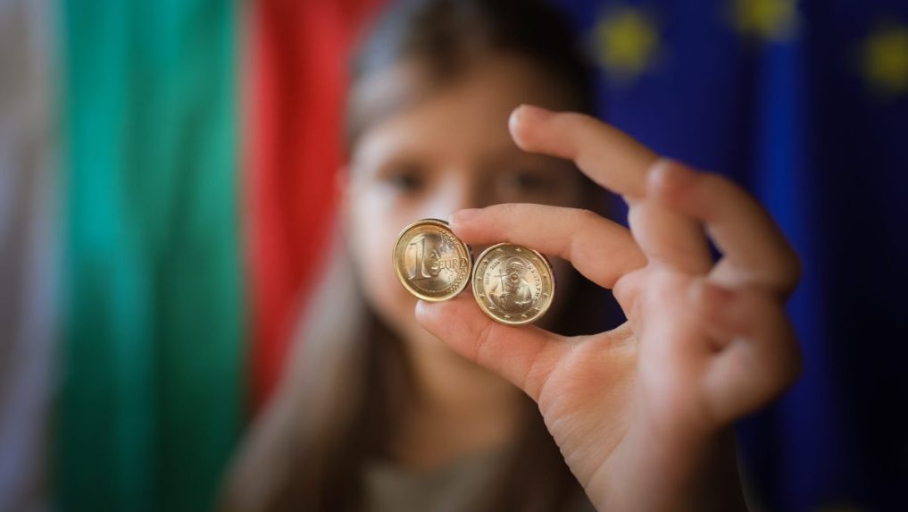 Dievča ukazuje nové euromince s bulharskými symbolmi v Sofii.