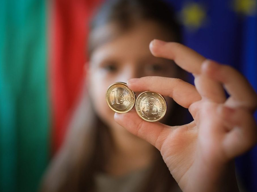Dievča ukazuje nové euromince s bulharskými symbolmi v Sofii.
