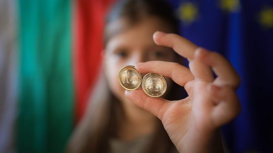 Dievča ukazuje nové euromince s bulharskými symbolmi v Sofii.