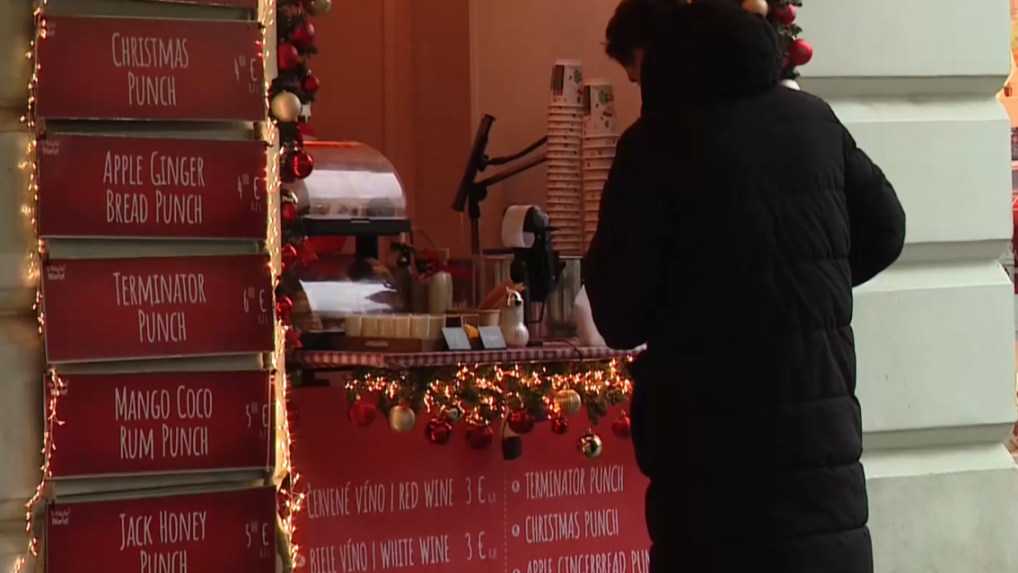 Na snímke muž stojí pri stánku na vianočných trhoch.