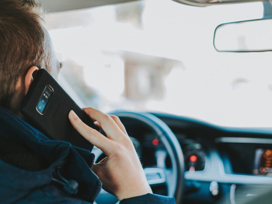 Na snímke muž telefonuje za volantom.