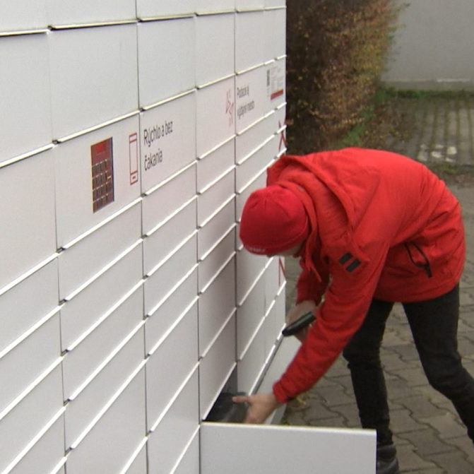 Kuriér vkladá balík do balíkoboxu
