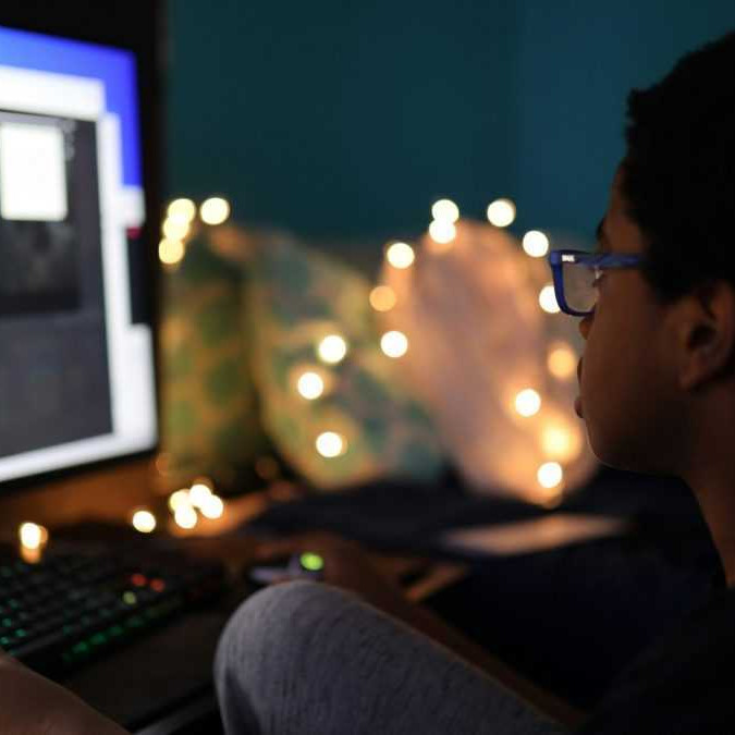 Dieťa sedí pred počítačom.