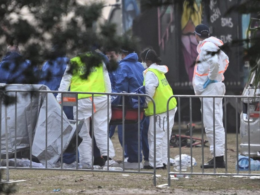 Forenzní technici skúmajú telo jednej z obetí streľby v Sydney.