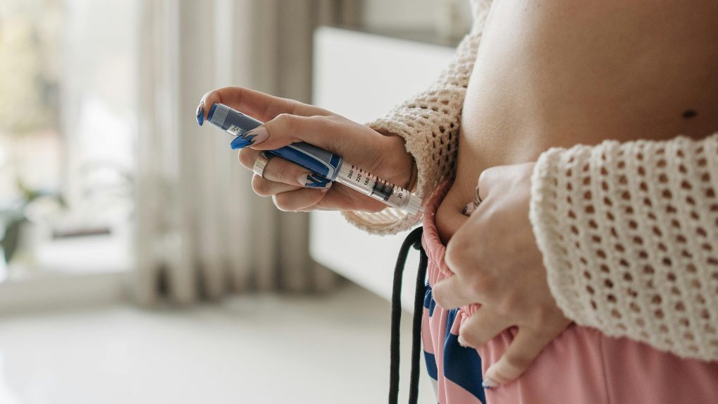 Žena si podáva inzulín injekciou pichnutím do brucha.