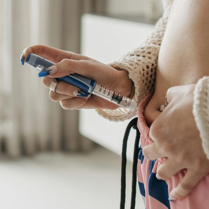 Žena si podáva inzulín injekciou pichnutím do brucha.