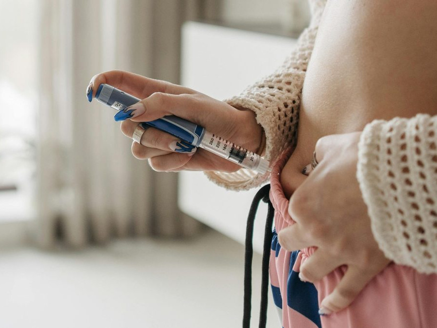 Žena si podáva inzulín injekciou pichnutím do brucha.