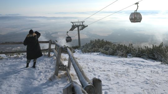 Na sníme je žena na svahu, nad ňou je lanovka, v pozadí zasnežená krajina vo Vysokých Tatrách.