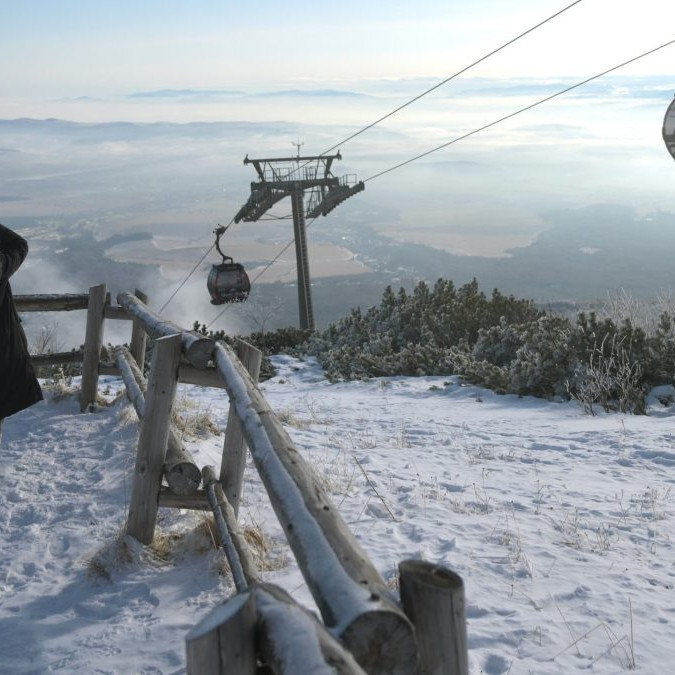 Na sníme je žena na svahu, nad ňou je lanovka, v pozadí zasnežená krajina vo Vysokých Tatrách.