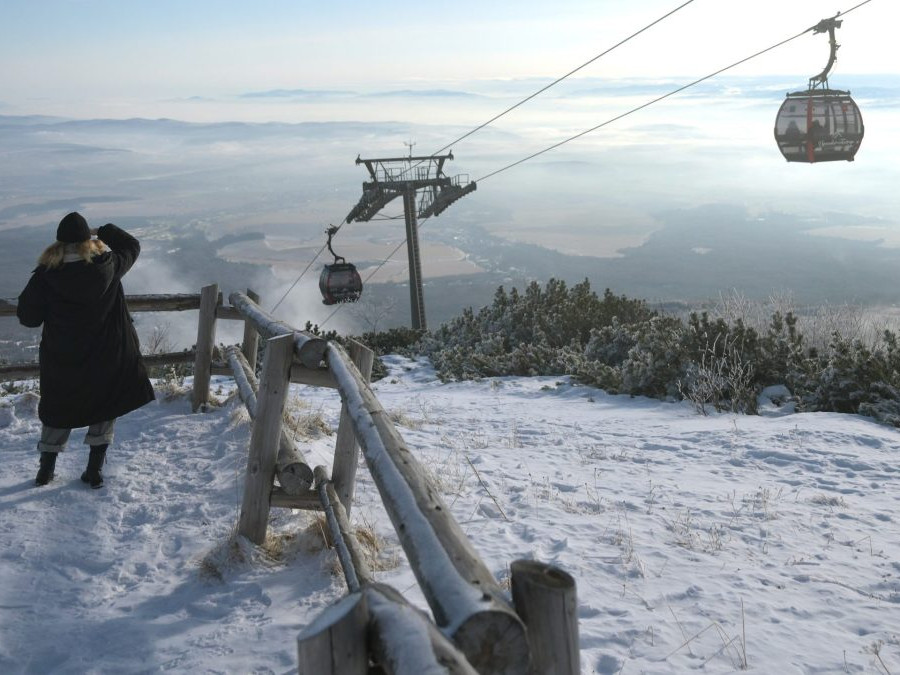 Na sníme je žena na svahu, nad ňou je lanovka, v pozadí zasnežená krajina vo Vysokých Tatrách.