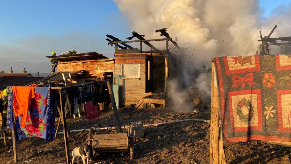 Požiar chatrčí v Arnutovciach. Z trosiek stúpa dym, zasahujú hasiči.