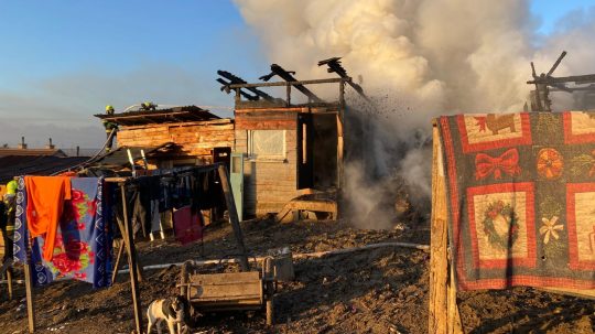 Požiar chatrčí v Arnutovciach. Z trosiek stúpa dym, zasahujú hasiči.