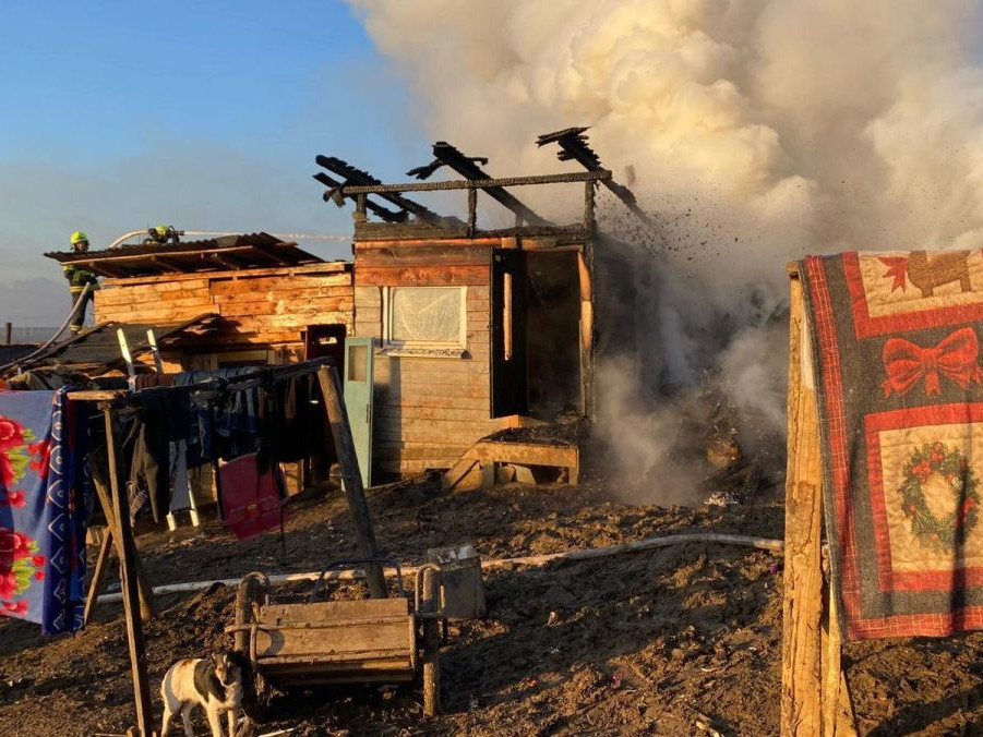 Požiar chatrčí v Arnutovciach. Z trosiek stúpa dym, zasahujú hasiči.