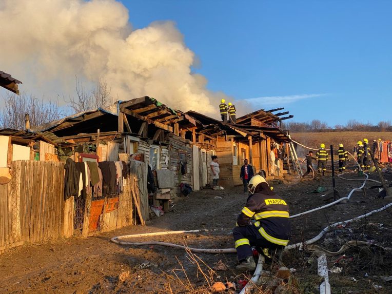 Požiar chatrčí v Arnutovciach. Z trosiek stúpa dym, zasahujú hasiči.