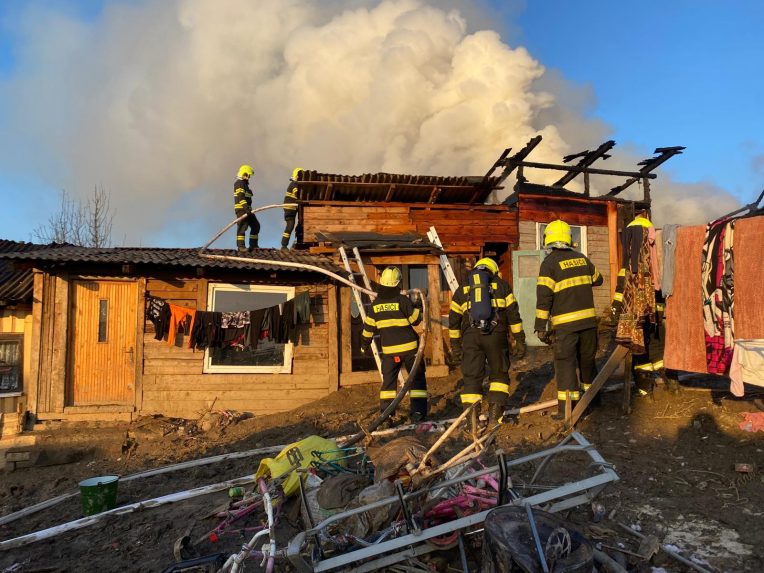 Požiar chatrčí v Arnutovciach. Z trosiek stúpa dym, zasahujú hasiči.