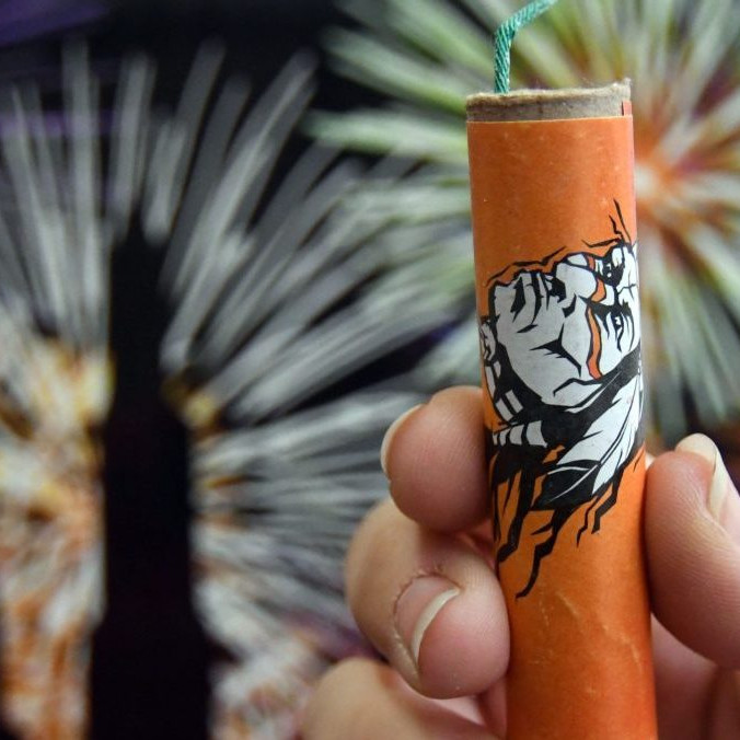 Žena drží v ruke petardu.