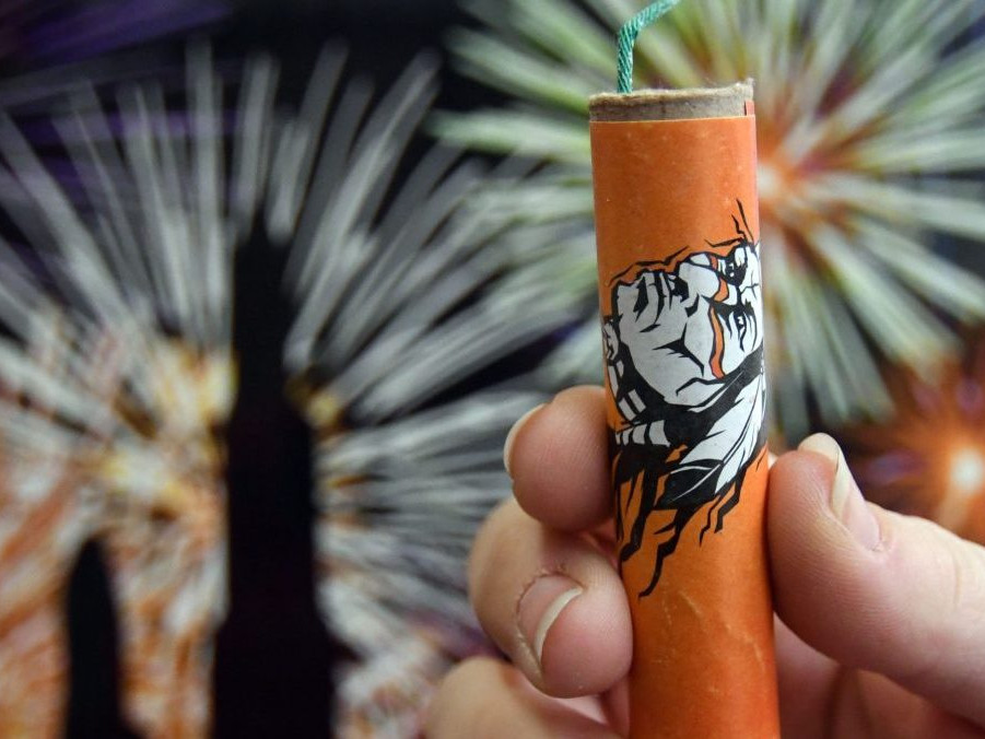 Žena drží v ruke petardu.