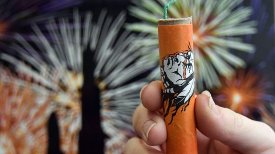 Žena drží v ruke petardu.