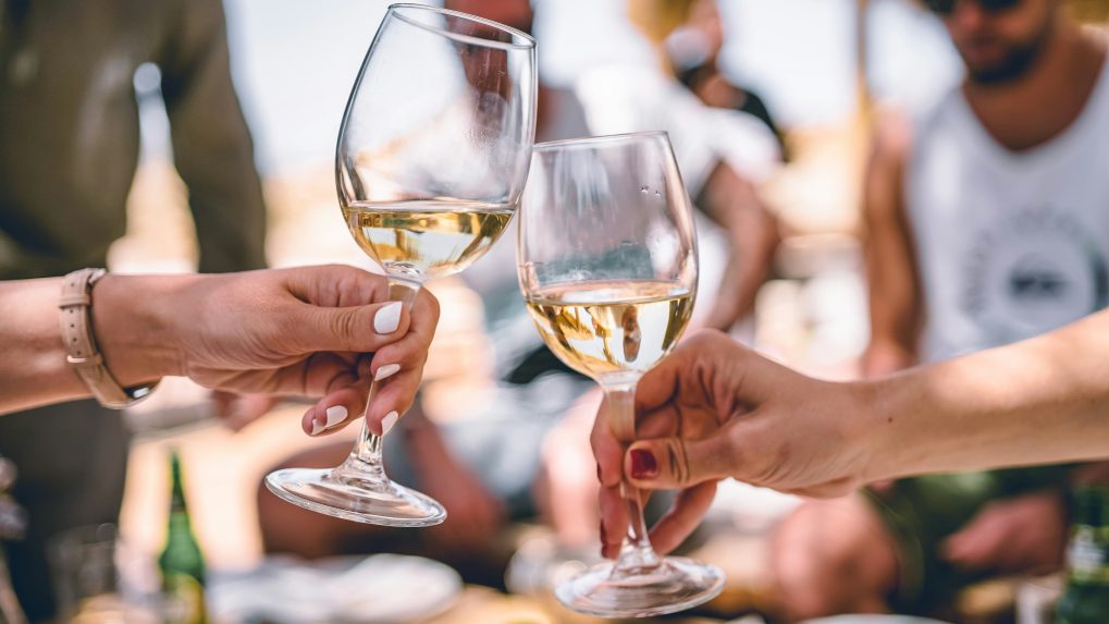 Dvojica si štrngá s pohármi, v ktorých je víno.