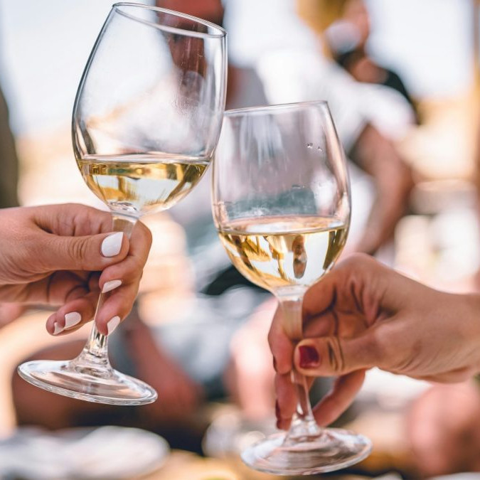 Dvojica si štrngá s pohármi, v ktorých je víno.