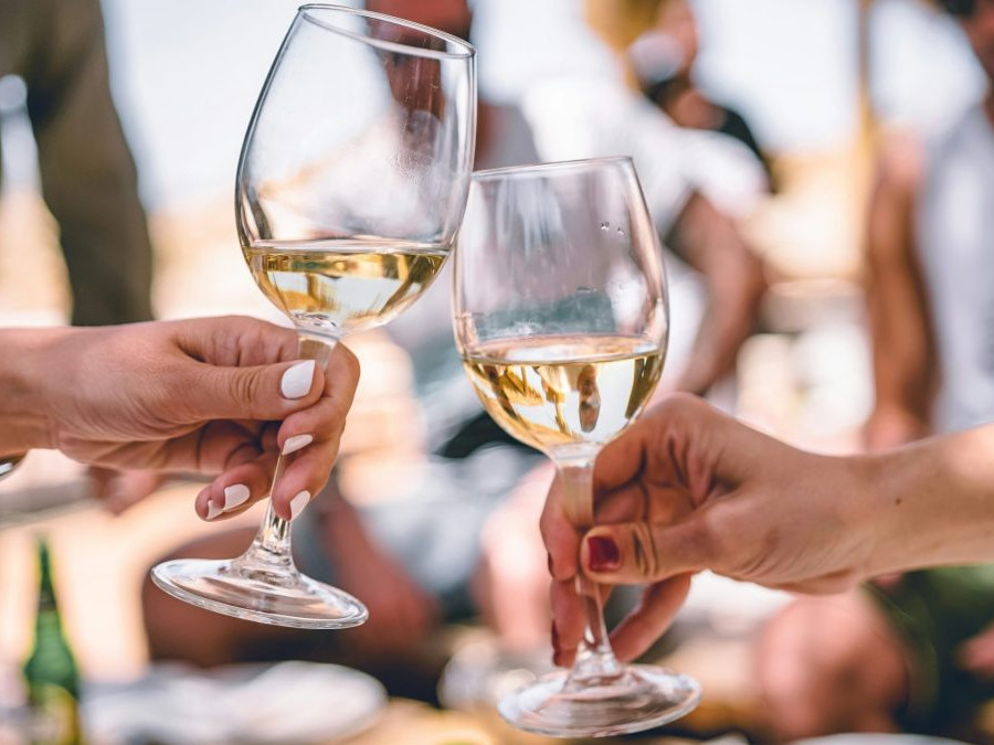 Dvojica si štrngá s pohármi, v ktorých je víno.