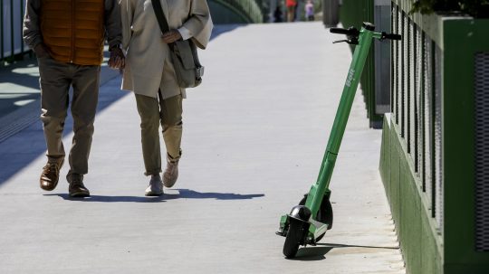 Na snímke elektrická kolobežka a dvojica chodcov.