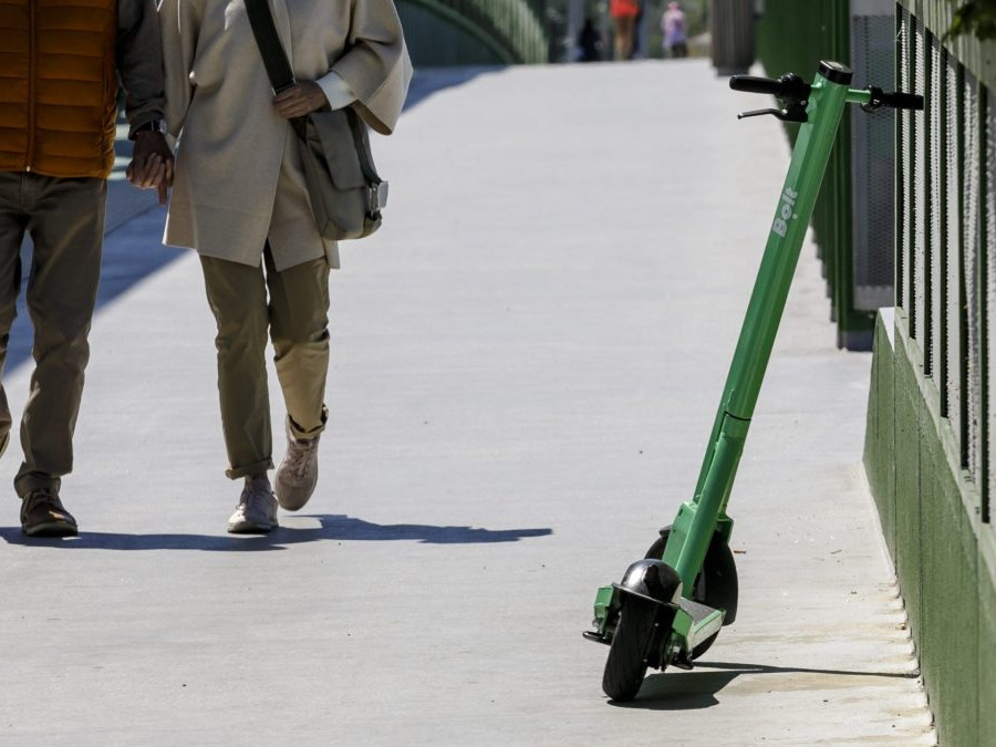 Na snímke elektrická kolobežka a dvojica chodcov.