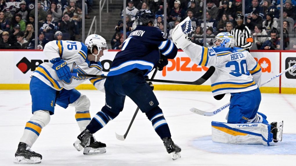 Brankár St. Louis Blues Joel Hofer (30) zasahuje, zatiaľ čo Tyler Tucker (75) bráni proti Vladislavovi Namestnikovovi z Winnipeg Jets.
